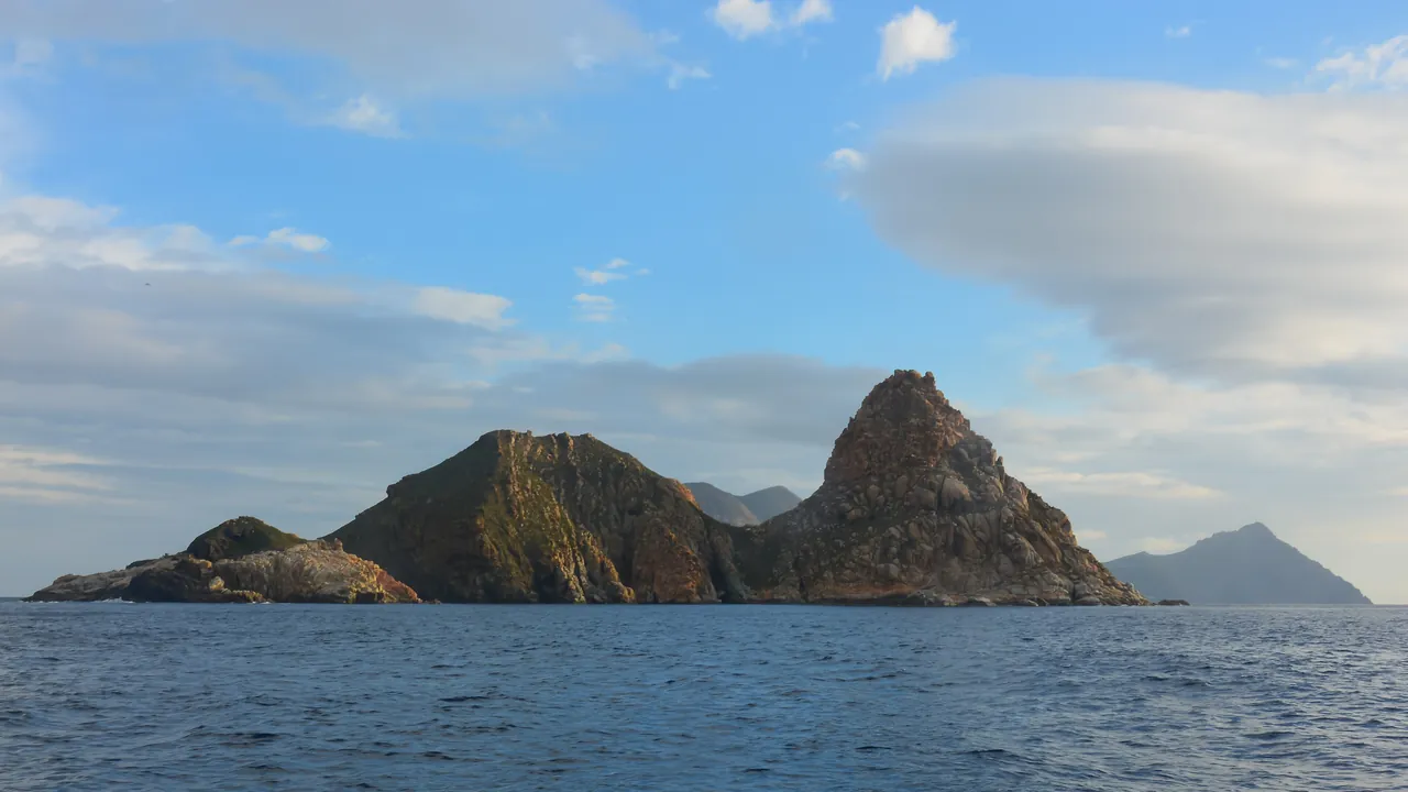 Les îlots rocheux du Galiton émergent d'une mer bleue sous un ciel nuageux